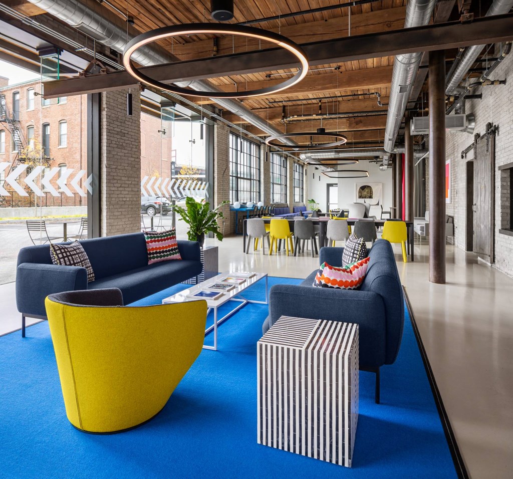 A modern living room with a blue carpet and yellow chairs.
