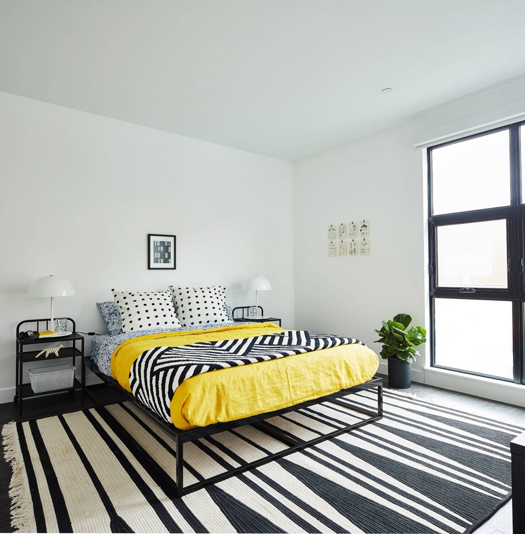 A bedroom with a bed and a plant.