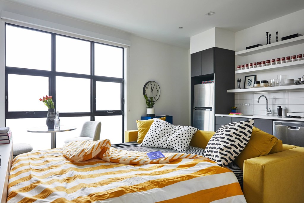 A bedroom with a bed, a chair, a clock, and a window.