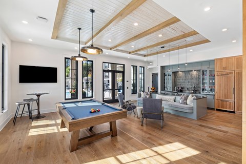 A pool table is in the middle of a room with a TV and a couch.