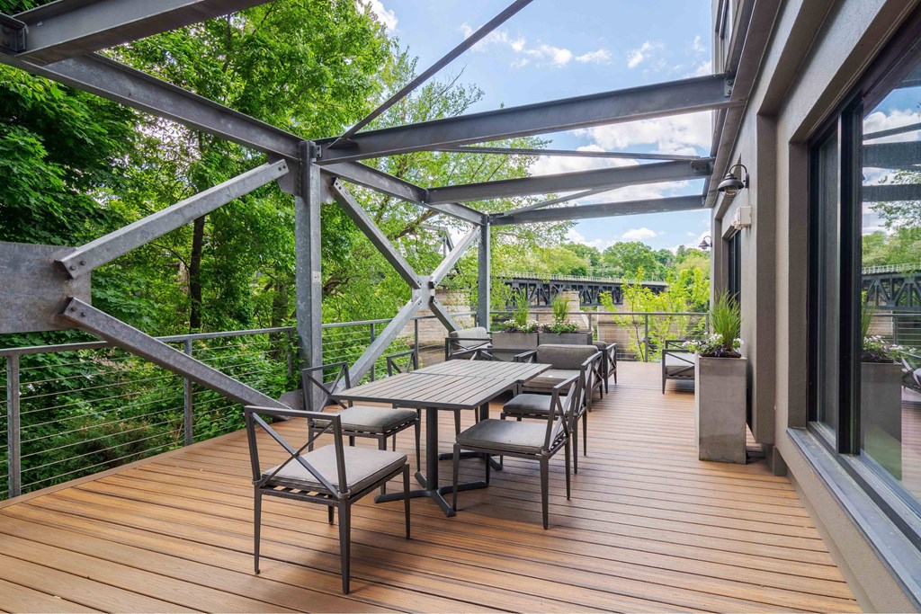 A wooden deck with a table and chairs under a metal pergola.