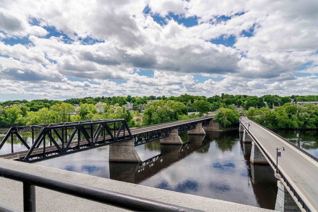 A bridge over a river with a cloudy sky above.