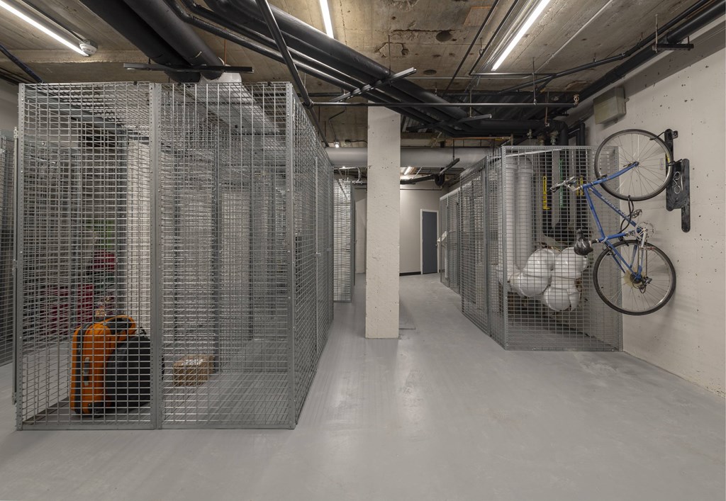 A bicycle is hanging on a wall in a room with metal cages.