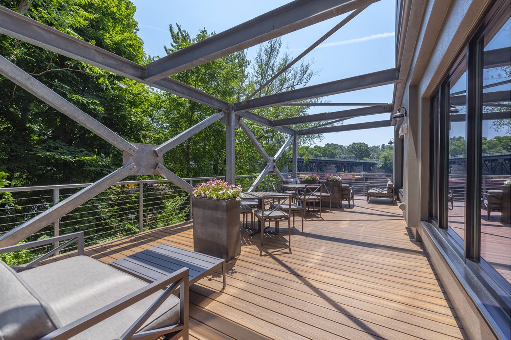 A wooden deck with metal railings and furniture.