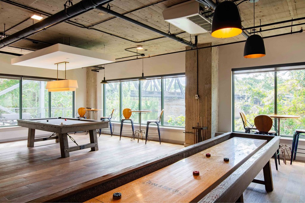 A pool table in a room with a high ceiling and large windows.