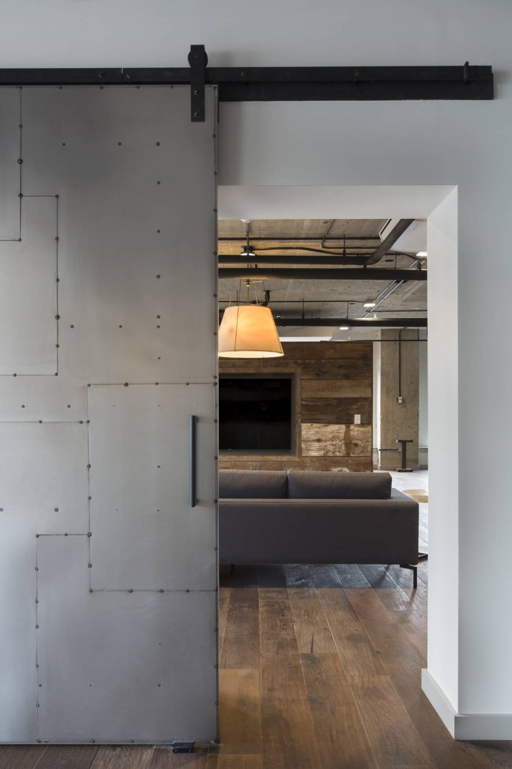 A room with a grey couch and a sliding door.