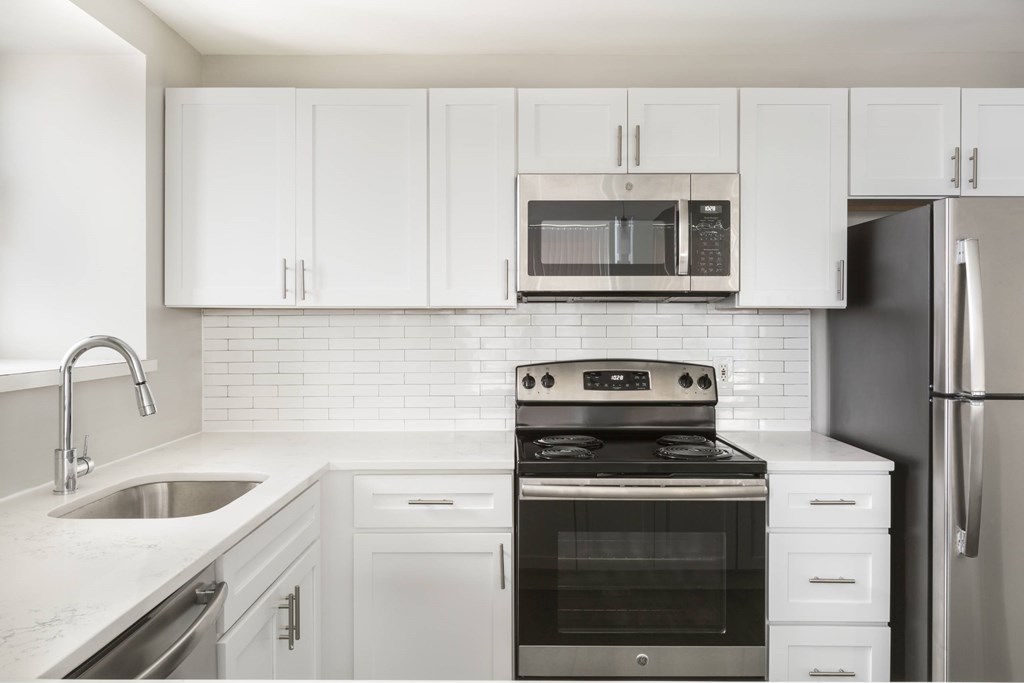 A modern kitchen with white cabinets and appliances.