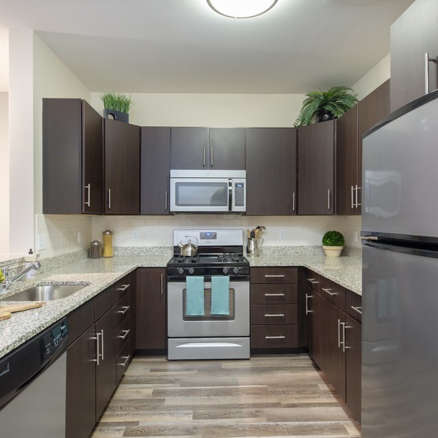 A kitchen with dark brown cabinets and a stainless steel refrigerator.