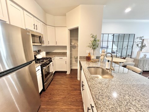 A kitchen with a stainless steel refrigerator and a granite countertop.