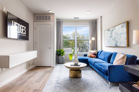 A living room with a blue couch and a flat screen TV mounted on the wall.