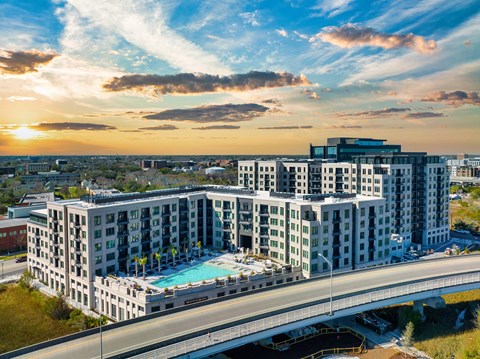 A large hotel with a pool is surrounded by a bridge and other buildings.