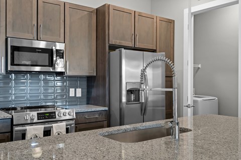 A modern kitchen with a stainless steel refrigerator and a granite countertop.