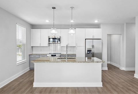 A modern kitchen with a central island and pendant lights.
