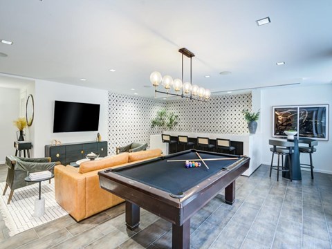 A pool table is in the middle of a room with a television and a couch.