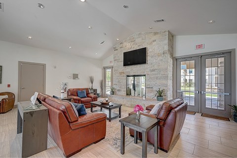 A living room with brown leather couches and a stone fireplace.