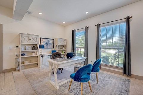 A room with a desk and blue chairs.