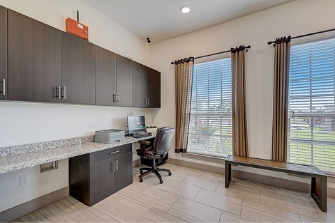 A room with a desk, chair, and a window with blinds.