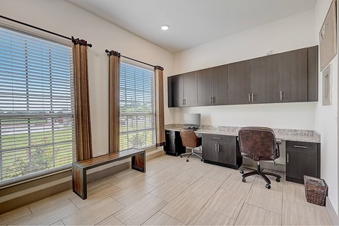 A room with a desk, chair, and window with blinds.