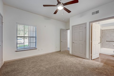 A room with a ceiling fan and carpeted floor.