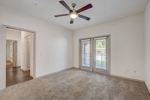 A room with a ceiling fan and carpeted floor.