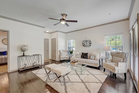 A living room with a white couch, a glass coffee table, and a ceiling fan.