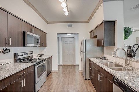 A kitchen with a stove, microwave, refrigerator, and sink.