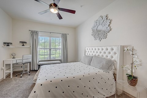 Bedroom with a bed, desk, chair, and window.