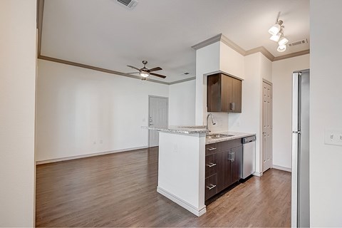 A kitchen with white cabinets and a countertop with a refrigerator to the right.