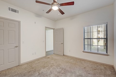 A room with a ceiling fan and a window with blinds.