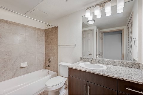 A bathroom with a white toilet, a bathtub, and a sink.