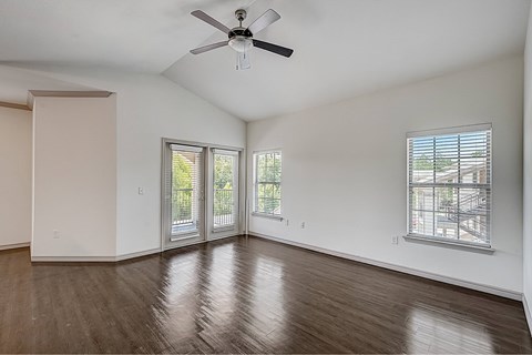 A room with a ceiling fan and sliding glass doors.
