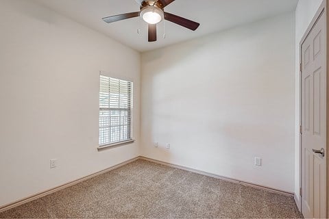 A room with a ceiling fan and a window with blinds.