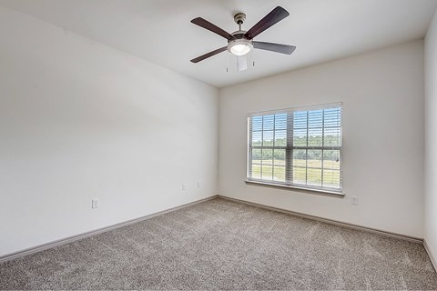 A room with a ceiling fan and a window with blinds.