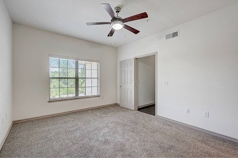 A room with a ceiling fan and a window with blinds.