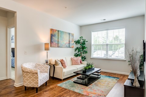 A living room with a white couch, a chair, a coffee table, and a painting on the wall.