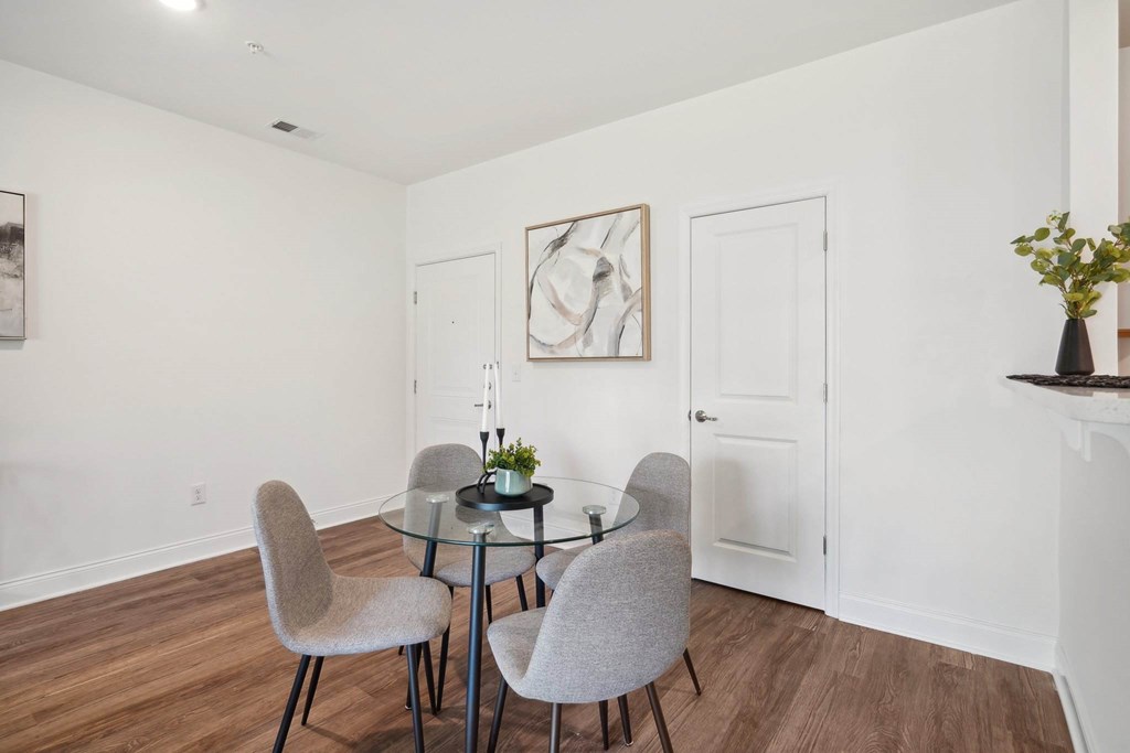 A dining room with a glass table and grey chairs.
