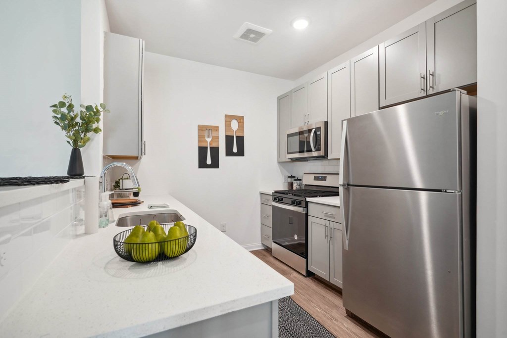 A kitchen with a stainless steel refrigerator and a bowl of bananas on the counter.