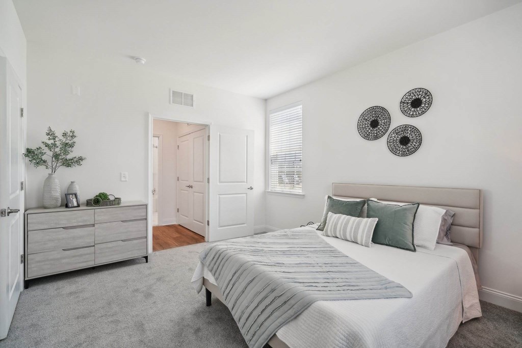 A bedroom with a bed, dresser, and two wall hangings.