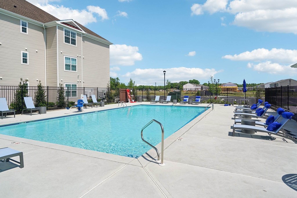 A large swimming pool with a diving board and lounge chairs.
