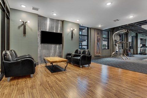 A modern living room with a wooden floor and a television mounted on the wall.