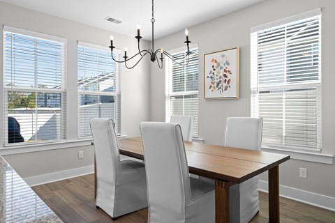 a dining room with a wooden table and chairs and windows