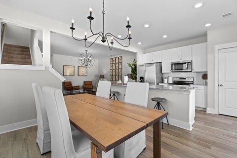 A modern kitchen with a wooden table and white chairs.