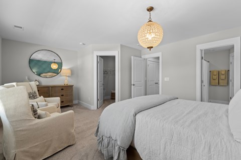 a white bedroom with a bed and a chair and a chandelier