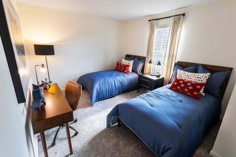 A bedroom with two beds and a desk.