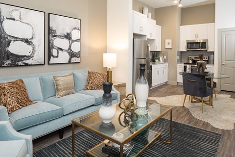 A modern living room with a blue couch and a coffee table with a glass top.