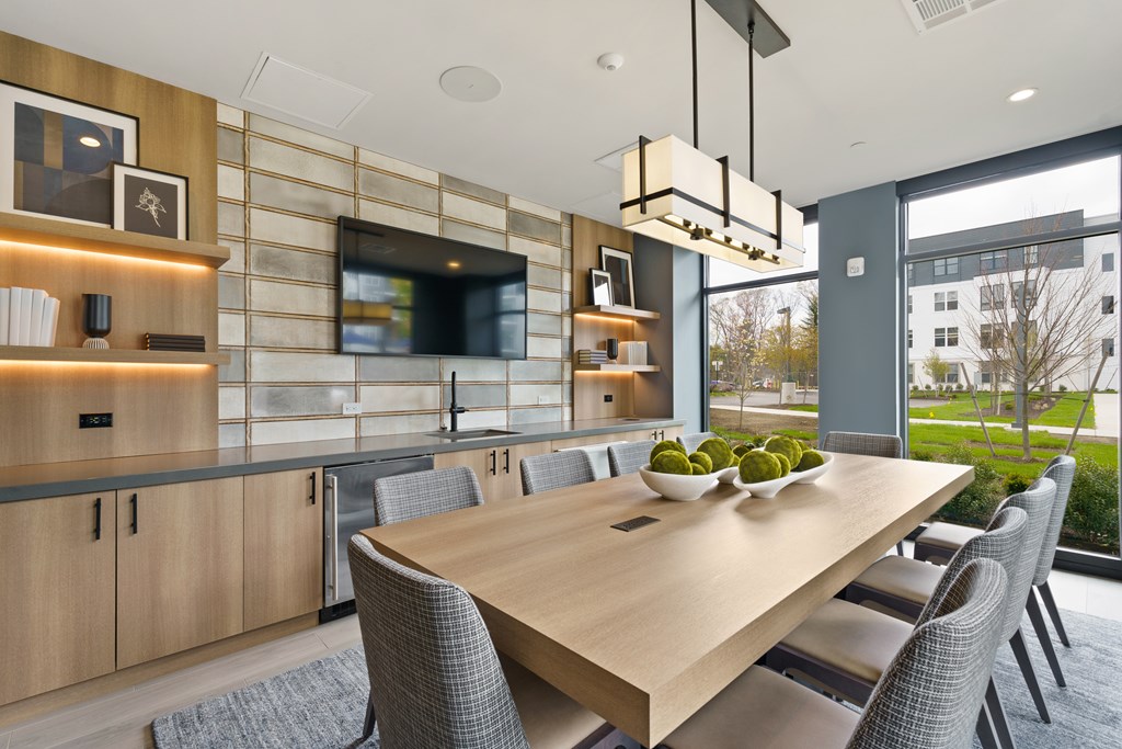 A modern dining room with a long wooden table and grey chairs.