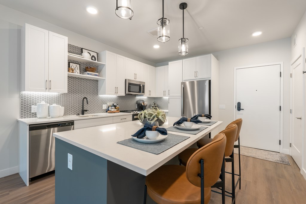 A modern kitchen with a large island and chairs.