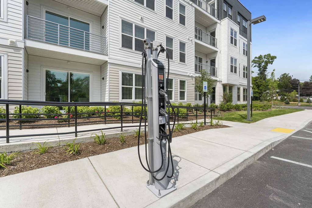 A parking meter is on the sidewalk in front of a building.