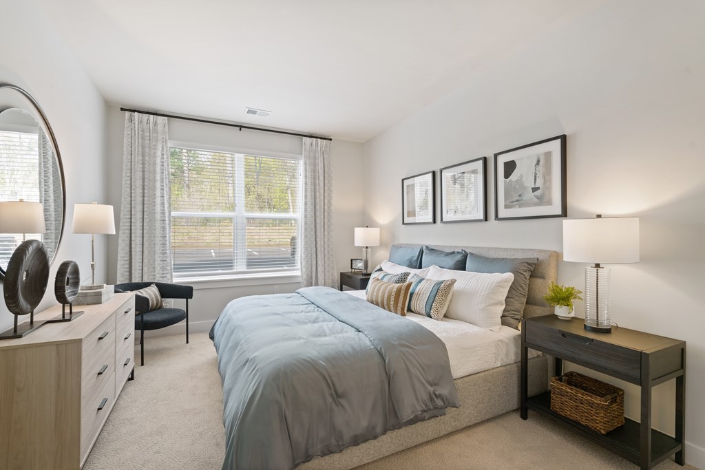 A bedroom with a large bed and a window with curtains.