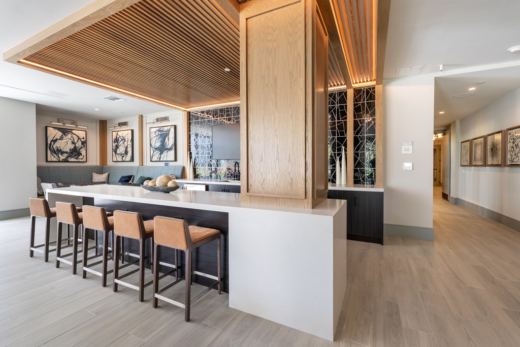 A modern bar with wooden stools and a counter.